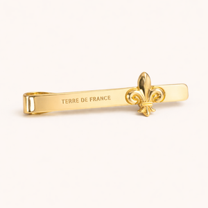 Pince à cravate Fleur de Lys laiton — vue de face sur fond gris, fabriquée en France