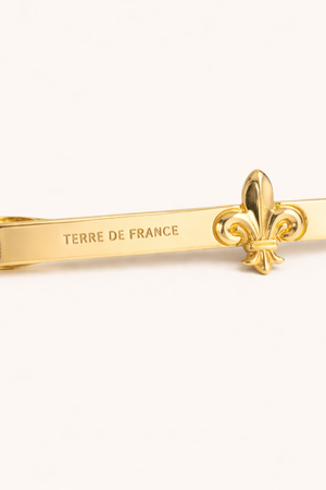 Pince à cravate Fleur de Lys laiton — vue de face sur fond gris, fabriquée en France